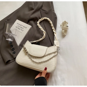 Detail of cream faux crocodile texture bag with woven handle and gold chain hardware