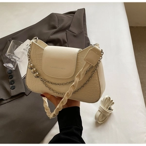Detail of cream-white crocodile pattern handbag with elegant metallic bead chain and logo