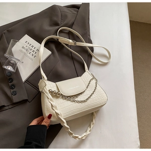 Detail of creamy white faux crocodile skin bag with silver chain and braided strap