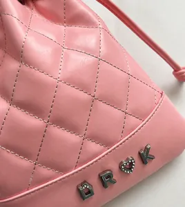 Detail of pink quilted leather drawstring bag with metal letters and diamond heart logo
