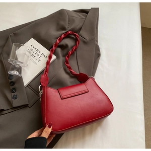 Detail of red faux leather shoulder bag with a woven twisted strap on a blazer
