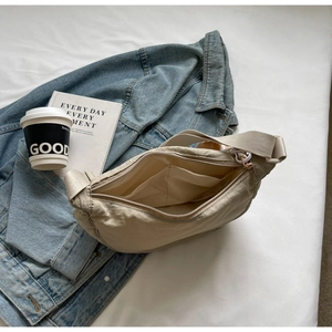 Détail du sac demi-lune en nylon beige avec poches intérieures et fermeture éclair