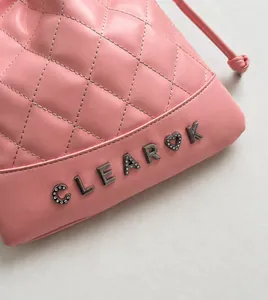 Detail of pink quilted leather bucket bag with crystal-encrusted metal logo lettering