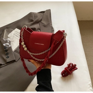 Close-up of red crocodile-embossed leather texture with stylish silver chain and bead details