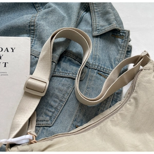 Détail du sac à bandoulière en nylon beige avec sangle réglable et fermeture éclair en métal