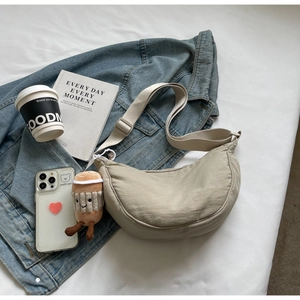Gros plan d'un sac demi-lune en nylon kaki avec large bandoulière et pendentif peluche