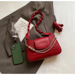 Detail of red crocodile pattern leather bag with woven strap and metal chain