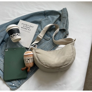 Détail du sac bandoulière croissant beige en nylon avec sangle ajustable et breloque