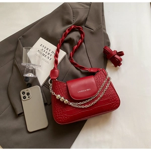 Detail of red crocodile pattern shoulder bag with woven strap and silver chain accent