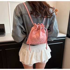 Pink quilted bucket backpack with rhombus stitching and metallic letters in a lifestyle view