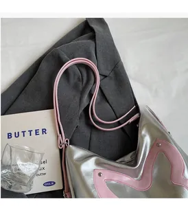 Detail of silver faux leather tote bag with pink wavy patchwork and slim handles