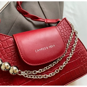 Close-up of red crocodile pattern leather texture with silver chain and metal bead