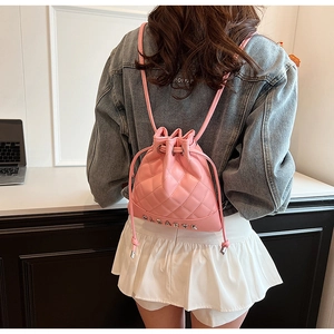Detailed back view of pink quilted bucket backpack with drawstring and silver letter logo