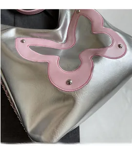 Close-up of silver metallic leather tote with pink butterfly patchwork and studded details