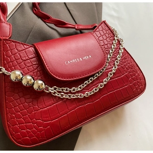 Close-up of red crocodile texture handbag with gold chain strap and bead details