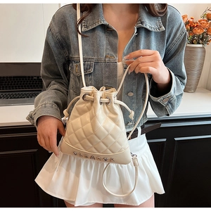 Detail of quilted bucket backpack in cream white with drawstring and metal logo
