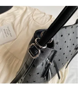 Detail of black polka dot handbag showing ribbon bow and silver hardware ring