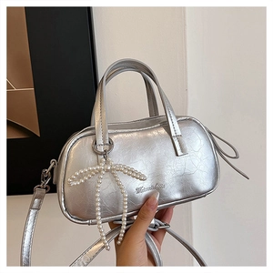 Detail of silver cracked texture handbag with pearl bow charm and adjustable strap