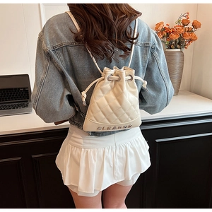 Close-up of cream quilted bucket backpack with drawstring closure shown on model