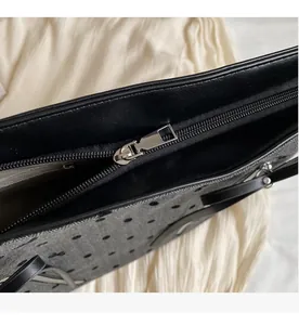 Close-up of smooth silver metal zipper on gray polka dot tote bag with leather trim