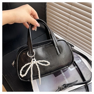 Close-up of black boston bag with cracked texture leather and pearl bow charm