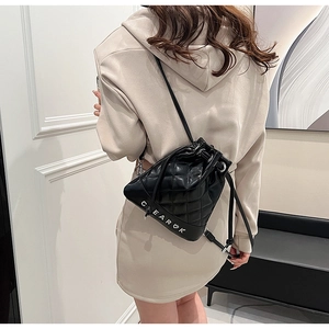 Detail of black quilted leather drawstring bucket bag showing silver metal hardware