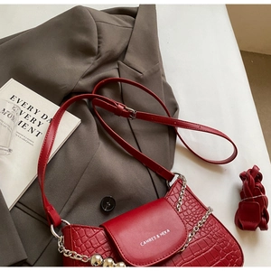 Detail shot of red crocodile embossed leather flap bag with silver chain and metal ball