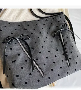 Close-up of grey herringbone tote bag with black polka dots and leather bow zippers