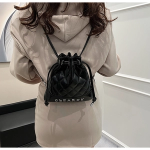 Close-up of quilted black patent leather bucket backpack with silver metal lettering
