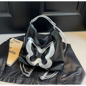 Close-up of black patent leather bag featuring a large silver hollow butterfly design