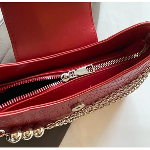Detail of red crocodile texture handbag with silver zipper and metallic ball chain