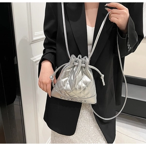 Detail of silver quilted bucket bag featuring drawstring closure and metal brand lettering