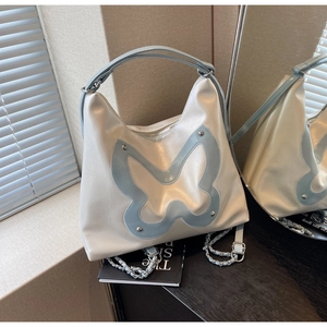 Detailed view of cream PU shoulder bag with blue butterfly leather patchwork and metal chain