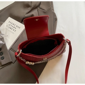 Detailed interior of red faux leather flap bag showing black lining and zip pocket