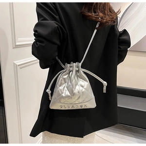 Detail of silver metallic quilted bucket backpack with drawstring and metal logo