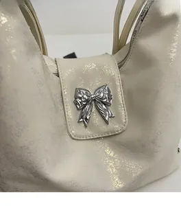 Close-up of beige tote bag with metallic texture fabric and a decorative metal bow