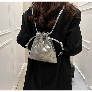 Detail of silver quilted bucket backpack with drawstring and metallic lettering design