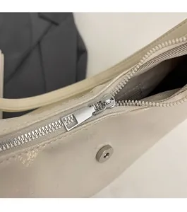Macro detail of silver metal zipper and glossy beige textured fabric on a fashion bag
