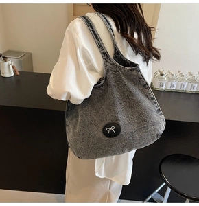 Grand sac cabas en jean délavé gris avec emblème de nœud, porté à l'épaule pour le quotidien