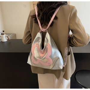 Silver Y2K backpack with pink butterfly patch and chain detail shown on a model