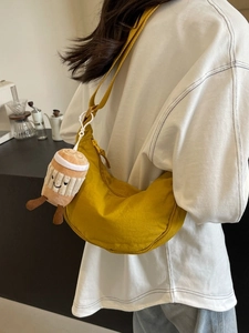 Sac bandoulière demi-lune en nylon jaune avec peluche café porté par un modèle