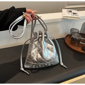 Detail of silver quilted bucket bag with metal letters and drawstring closure