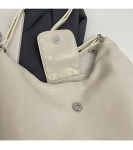Close-up of magnetic snap closure and zipper pocket detail on cream tote bag