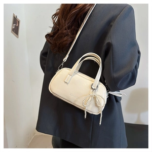 Model view of cream white crossbody bag with a pearl bow charm and silver hardware