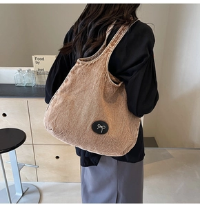 Détail d'un grand sac cabas en denim avec un nœud noir porté par un mannequin de dos