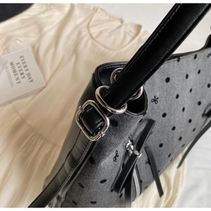 Detail of grey canvas tote with polka dots, bow patterns and silver metal hardware