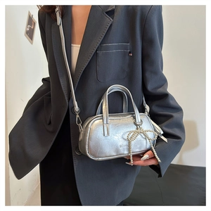 Detail of silver metallic mini handbag with pearl bow charm and crossbody strap
