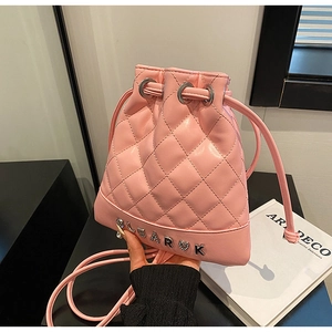 Close-up of pink quilted bucket backpack with heart charm and leather drawstring detail