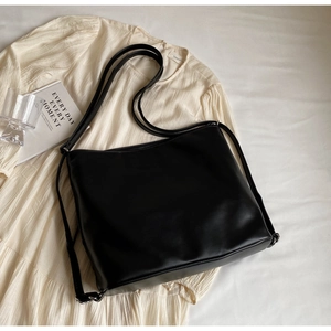 Detailed close-up of a black matte leather tote bag with fine texture and slim straps