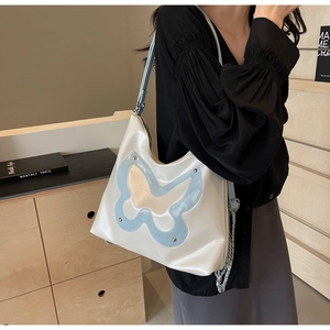 Close-up of cream hobo bag featuring blue butterfly applique and silver chain detail